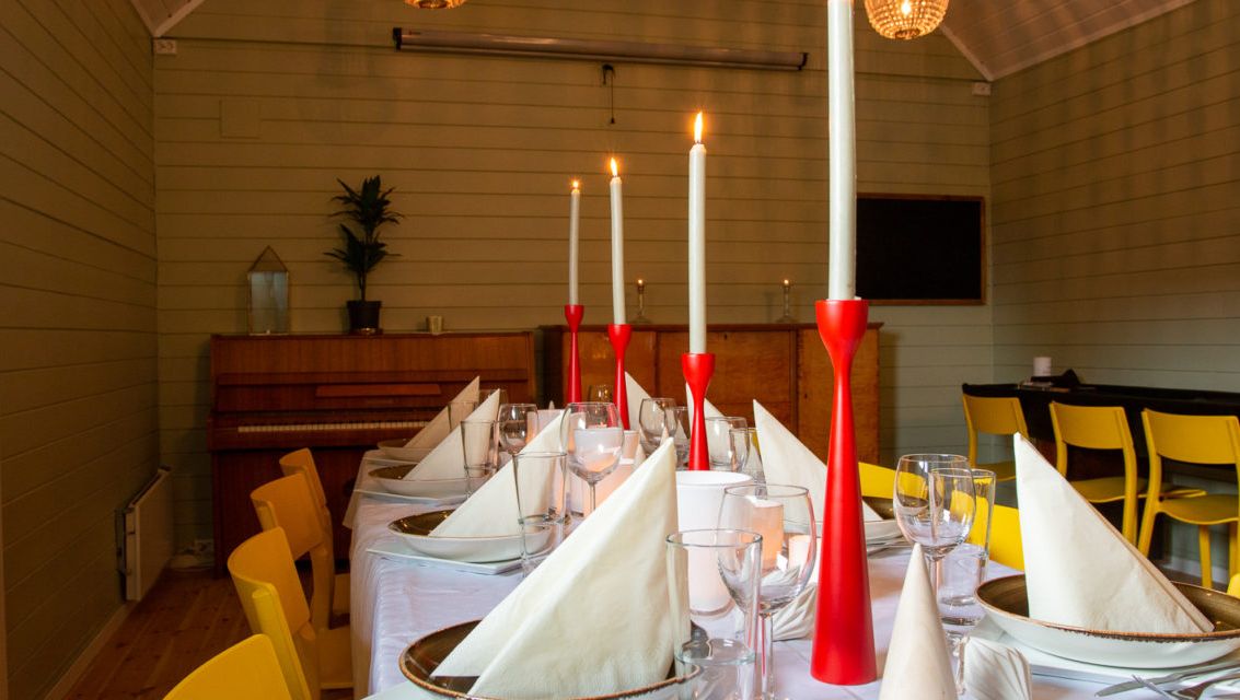 Langbord med røde lysestaker dekket til middag